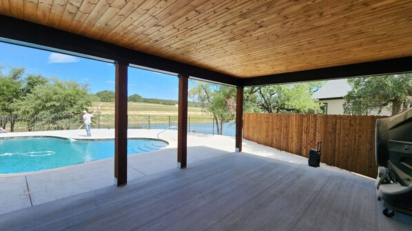 An outdoor patio with a wooden ceiling, a pool, and a view of a lake.