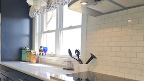 Een keuken met donkere kastjes, een wit aanrechtblad en een raam met een decoratieve valance.