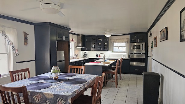 Een kleine keuken met donkere kastjes, een centraal eiland en een eetgedeelte met een tafel voor vier personen.
