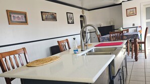 Een keuken met een centraal eiland, houten stoelen, een koelkast en een eettafel met stoelen.