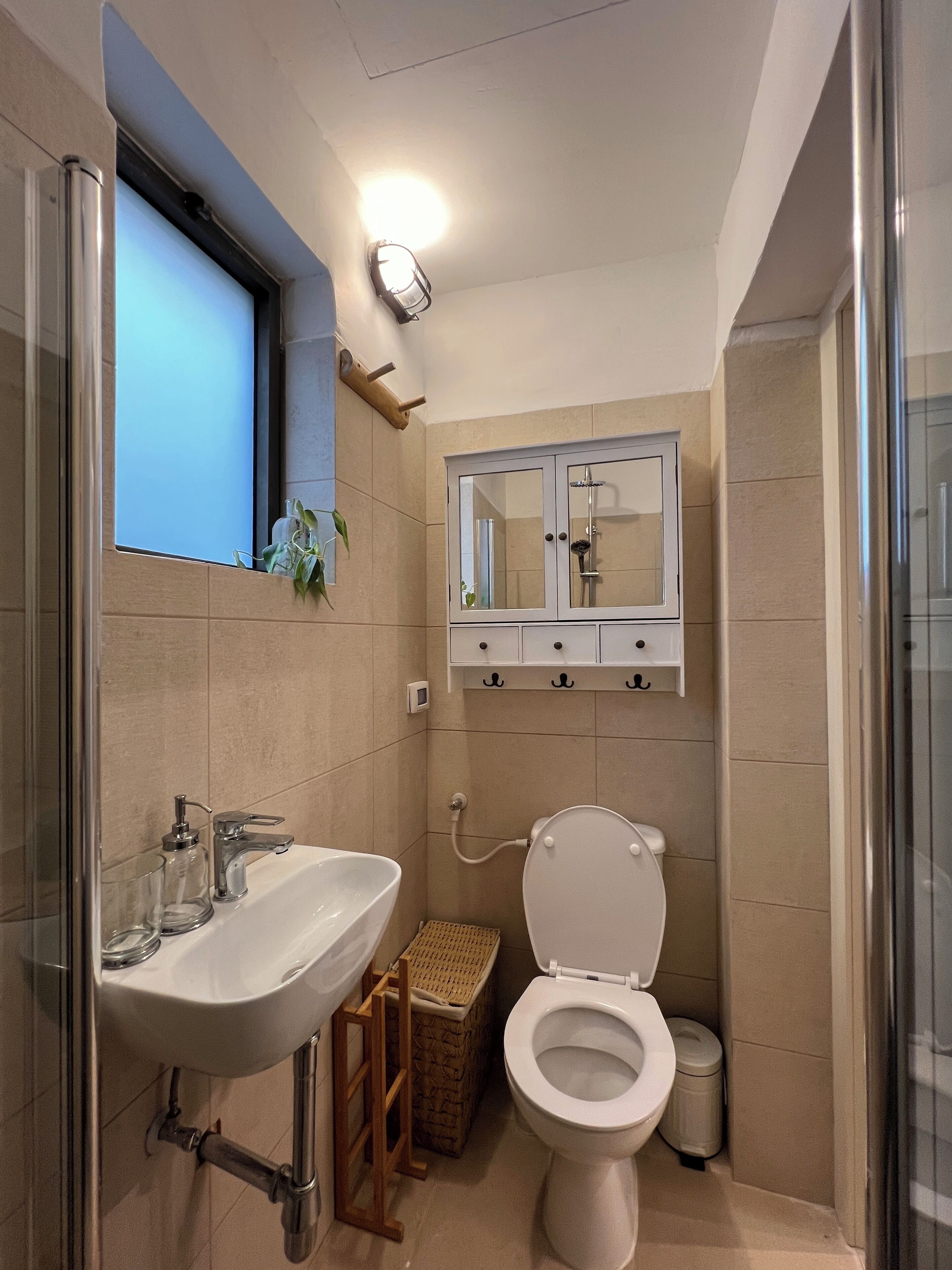 A compact bathroom with a sink, toilet, and a mirror cabinet.