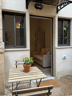An outdoor seating area with a wooden table and bench, a potted plant, and a beige sofa. - Haifa Downtown Eco Apt by Sea N' Rent (Haifa)