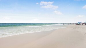 A beach with a wide sandy shore, calm waves, and a clear sky.