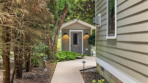 A pathway leading to a small shed with a door and two wall-mounted lights. - Luxe Cape May Point Home near Beach +Peloton (Cape May)