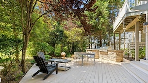 A wooden deck with outdoor furniture, a stone barbecue, and a pergola structure. - Luxe Cape May Point Home near Beach +Peloton (Cape May)