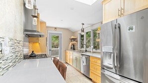 A modern kitchen with a stainless steel refrigerator, a gas stove, and wooden cabinets. - Luxe Cape May Point Home near Beach +Peloton (Cape May)
