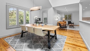A modern dining area with a wooden table, white chairs, and a grey rug. - Luxe Cape May Point Home near Beach +Peloton (Cape May)