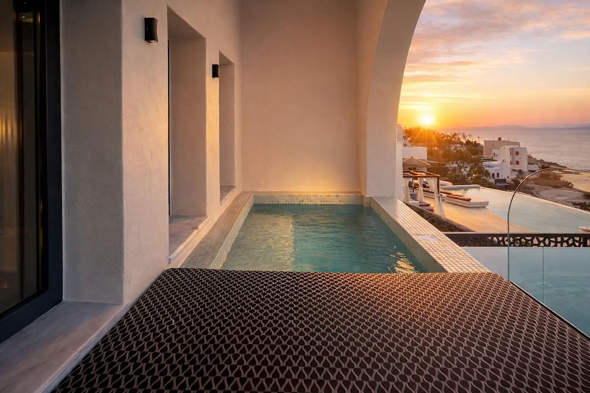 A balcony with a pool, overlooking a coastal area during sunset.