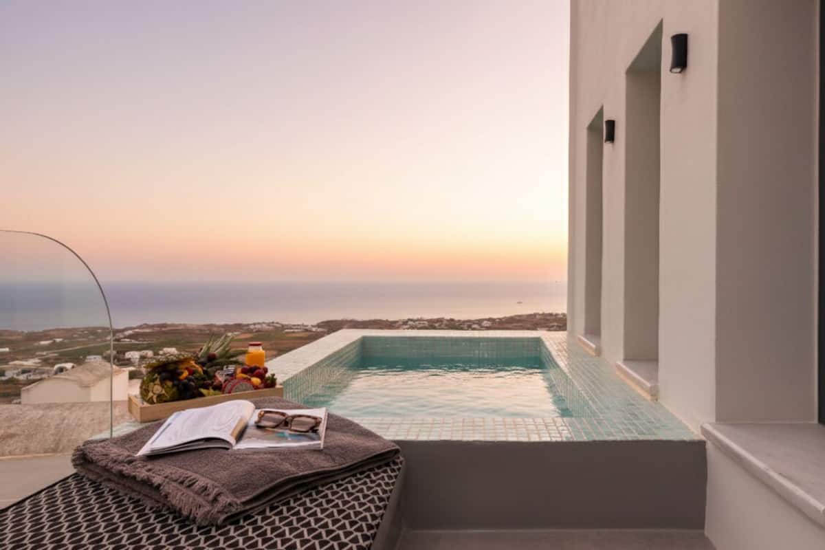 A rooftop pool with a view of the sea, a book, and a fruit basket.