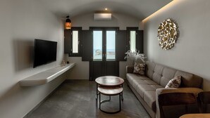 A modern living room with a flat-screen TV, a round wooden table, a sofa, and a decorative wall piece.