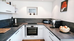 A modern kitchen with white cabinets, a Bosch oven, a microwave, and a coffee machine. - GardenOasis: Exclusive Seehalde apartment (Schluchsee)
