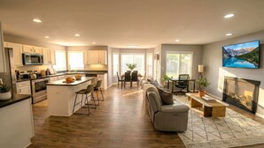 A modern kitchen with a central island, dining area with a sofa, and a fireplace. - Renovated 3BR — King Suite, Laundry, Parking (New Castle)