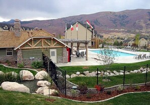 A residential area with a swimming pool, a stone house, and flags. - 3 BR 3.5bth with 2 En-Suite King Bedrooms (Eden)