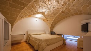 A bedroom with a vaulted stone ceiling, a bed, a desk, and a television. - BOUTIQUE HOTEL HISTORIC CENTER LECCE (Lecce)
