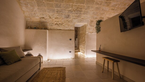 A cozy living room with a stone ceiling, a sofa, a coffee table, and a TV mounted on the wall. - BOUTIQUE HOTEL HISTORIC CENTER LECCE (Lecce)
