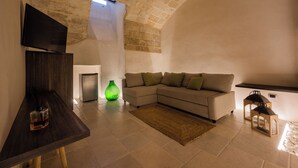 A living room with a stone ceiling, a sofa, a TV, and a green vase. - BOUTIQUE HOTEL HISTORIC CENTER LECCE (Lecce)