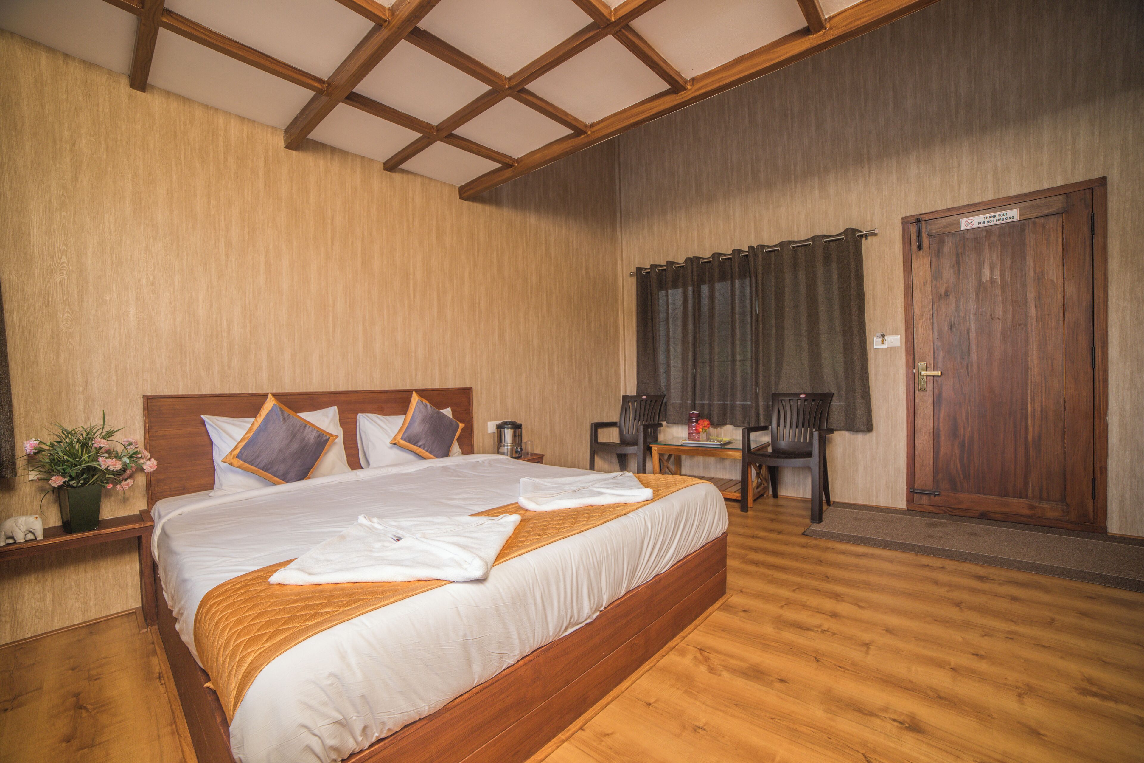 Une chambre d’hôtel avec un lit en bois, un bureau, une chaise et une porte.