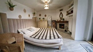Une chambre à coucher comprenant un lit, une chaise, une commode, une cheminée et des éléments décoratifs sur les murs.