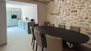 Ein Essbereich mit einer Steinwand, einer Küche im Hintergrund und einer Decke mit freiliegenden Balken.