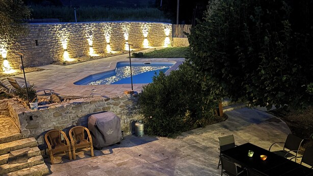 Eine Terrasse im Freien mit Steinboden, einem Pool und Steinmauern.