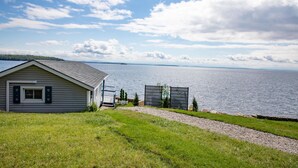 A house with a view of a lake, a gravel path, and a grassy area. - ZaLo House Waterline cabin with Hot Tub Pets (Peru)