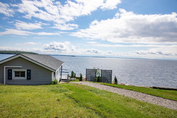 Une maison avec vue sur un lac, un chemin de gravier et une zone herbeuse.