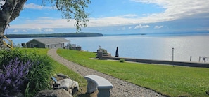 Une vue sur le lac, avec un belvédère, un banc en pierre et un petit bâtiment.