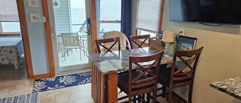 A kitchen with a dining area, a TV, and a view of the ocean.