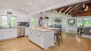 A spacious kitchen with white cabinets, a central island, and pendant lighting. - Remodeled, Family-Friendly Home in Private Community on Candlewood Lake (New Fairfield)
