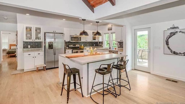 A spacious kitchen with a large island, pendant lighting, and a view to the outdoors. - Remodeled, Family-Friendly Home in Private Community on Candlewood Lake (New Fairfield)