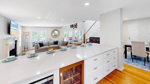 A spacious living area with a large island, a fireplace, and a dining area with a staircase. - Gorgeous home in Wild Dunes with parking on Palm Blvd. (Isle of Palms)