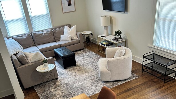 Una sala de estar moderna con sofá, una mesa de centro y una zona de comedor con una mesa y sillas de madera.