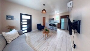 A modern living room with a sofa, a coffee table, and a dining area with chairs.