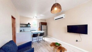A modern kitchen with a dining area, a flat-screen TV mounted on the wall, and a unique wooden table centerpiece.
