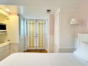 Une chambre à coucher avec un lit, une armoire, une télévision et une fenêtre.