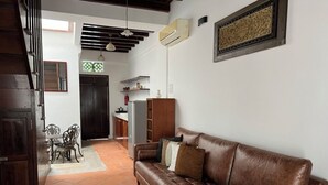 A living room with a brown leather sofa, a dining table with chairs, a kitchen area, and a staircase. - Chulia Corner, cosy townhouse in Georgetown Unesco Heritage, Penang.  (George Town)