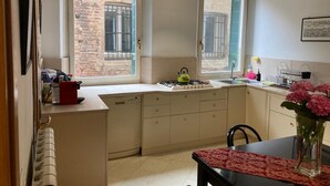 Una cocina funcional con dos ventanas, estufa a gas y pileta.