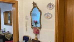 Un comedor con una mesa de madera y cuatro sillas tapizadas, un espejo y platos decorativos en la pared.