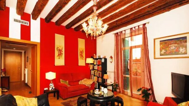 Una sala de estar con un sofá rojo, una mesa de centro negra y una estantería.