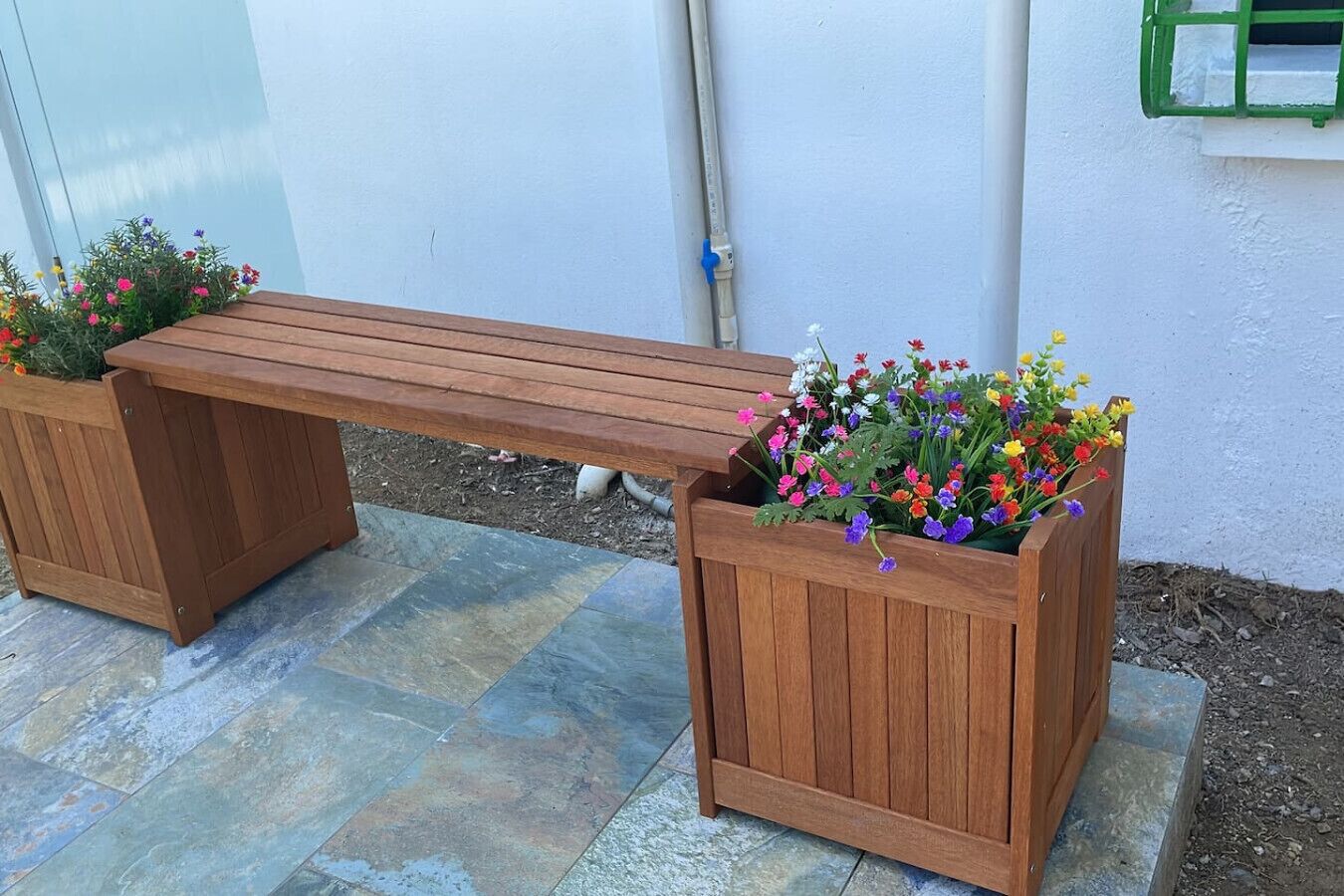 A wooden bench with two flower planters on either side.