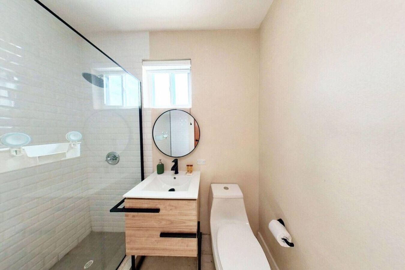A compact bathroom with a glass shower enclosure, a white sink with a mirror, and a white toilet.