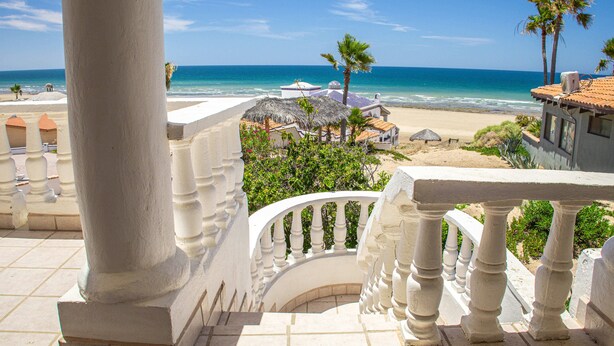 A balcony with a view of the beach and ocean.