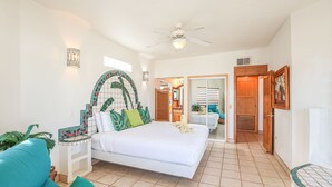 A spacious bedroom with a large bed, a ceiling fan, and a view of the bathroom.