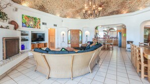 A spacious living area with a brick ceiling, a large woven sofa, a fireplace, and a television.