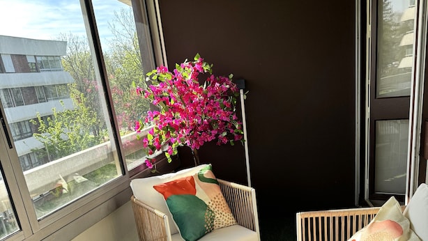 Una sala de estar moderna con una mesa de centro de vidrio, sillas de mimbre y un sofá con cojines de colores.