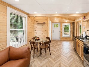 A wooden interior with a dining area, kitchen, and a sofa.