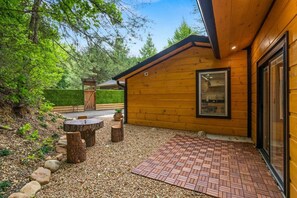 A wooden cabin with a patio area featuring a brick floor and wooden stools.
