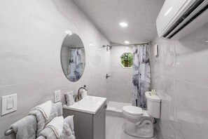 A modern bathroom with a vanity, toilet, and shower.