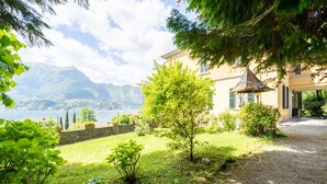 A house with a garden, a small tree, and a view of a lake and mountains. - Villa Emilia Apartment by Wonderful Italy (Bellagio)
