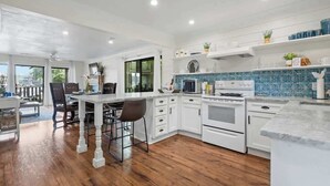 A modern kitchen with white cabinetry, a central island, and a blue backsplash. - Waterfront Condo Retreat in Garland County (Garland County)